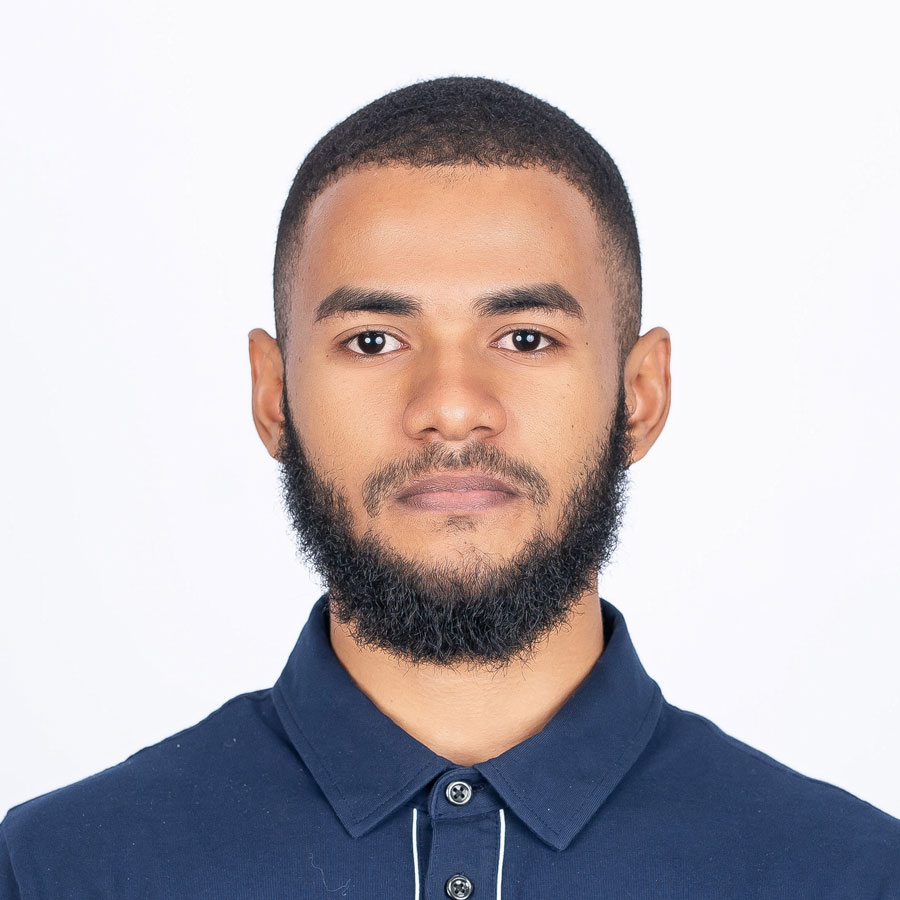 Persona de pie en la orilla del mar, con el agua tocando sus pies, bajo un cielo parcialmente nublado en la playa.